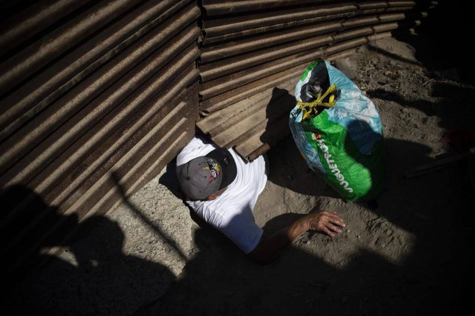 <p>A Central American migrant passes under a border fence between Mexico and the United States, near El Chaparral border crossing, in Tijuana, Baja California State, Mexico, on November 25, 2018.</p>