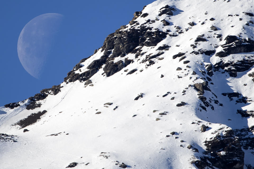 The moon is seen behind a mountain prior to the downhill run of the men's Alpine combined race at the Alpine Skiing FIS Ski World Cup in Wengen, Switzerland, Friday, Jan. 17, 2020. (Peter Klaunzer/Keystone via AP)