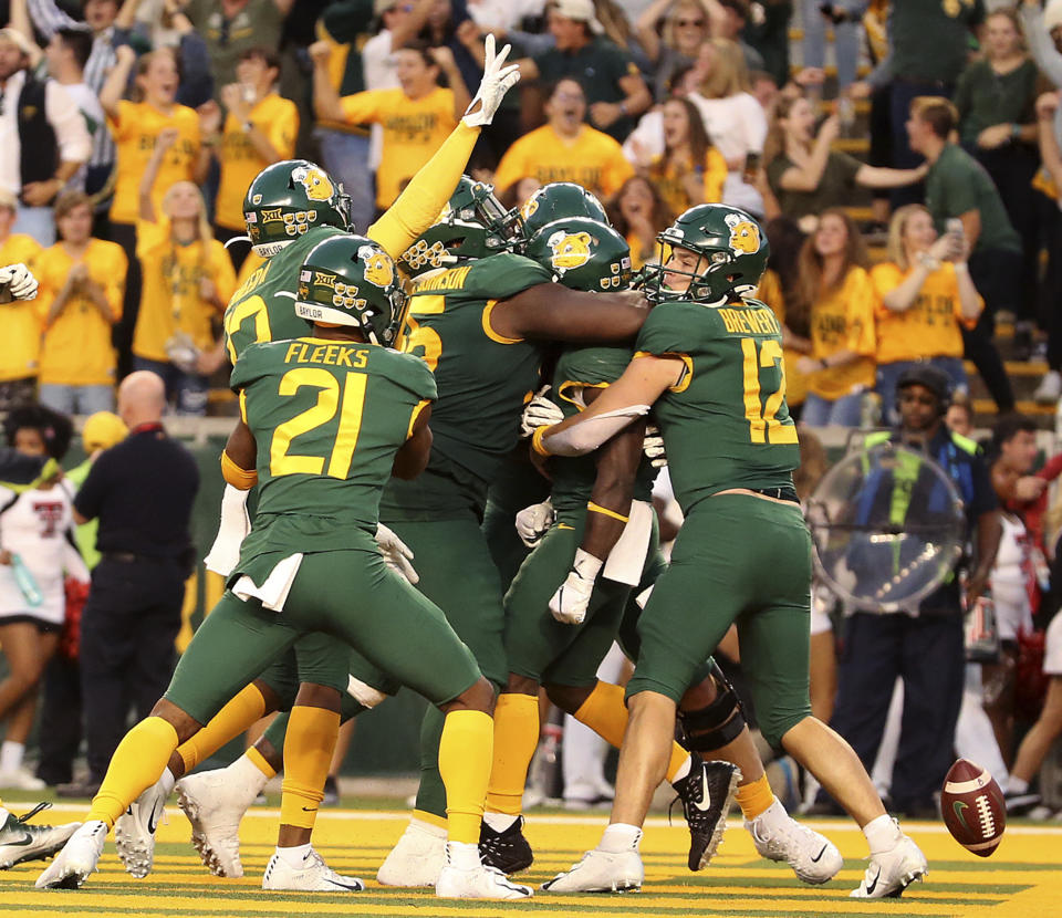 Baylor quarterback Charlie Brewer (12), right celebrates a touchdown with his teammates against Texas Tech in the second overtime of a NCAA college football game in Waco, Tex.,Saturday, Oct. 12, 2019. Baylor won 33-30. (AP Photo/Jerry Larson)