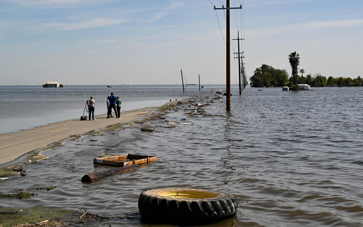 Media work Tuesday, April 25, 2023 on Sixth Avenue at the edge of the flooded Tulare Lake south of the Tule River in Corcoran, Calif.