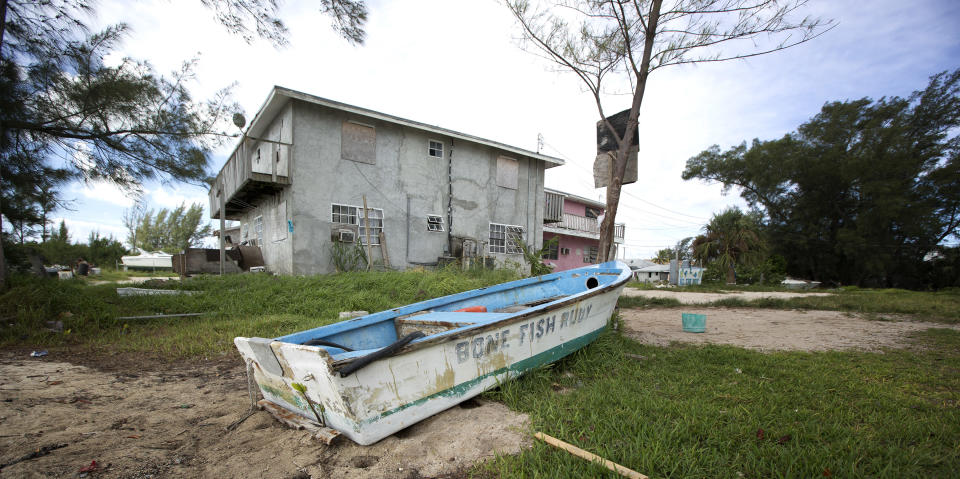 In this Sept. 11, 2013 photo, an old fishing boat sits next to a homemade basketball goal at an apartment complex in Bimini, Bahamas. Changes are coming fast to Bimini. Malaysia-based Genting Group is spending at least $300 million on Resorts World Bimini, quickly becoming the largest employer in the cluster of islands and creating sharp new demand for housing, but there is also an uneasiness about what may happen to the delicate ecosystem and rough-around-the-edges atmosphere that are key to Bimini’s identity as a sport fishing capital of the world. (AP Photo/J Pat Carter)