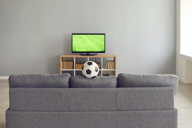 TV showing football in front of a sofa.