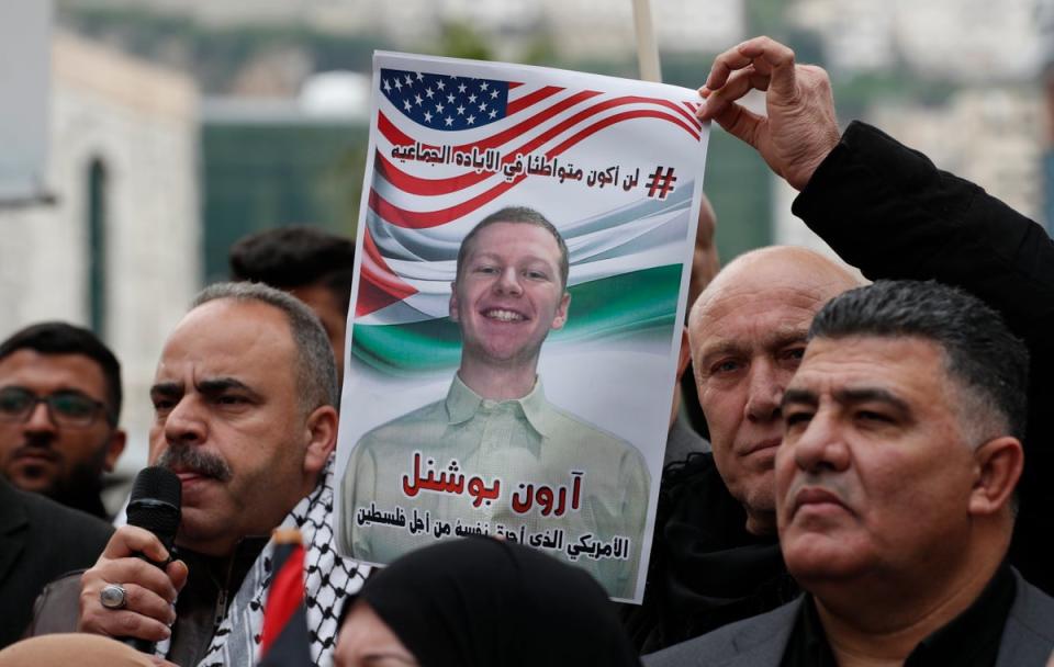 A man holds up a photo of late US airman Aaron Bushnell, who died of his injuries after setting himself on fire outside the Israeli embassy in Washington DC (EPA)