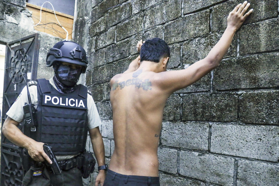 Un hombre se mantiene con los brazos en alto mientras la policía revisa si lleva armas o drogas, parte de un operativo para combatir a grupos criminales y extorsionadores, el jueves 4 de abril de 2024, en Guayaquil, Ecuador. (AP Foto/César Muñoz)