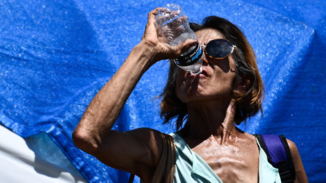 A person drinks a bottle of water during a heat wave in Phoenix