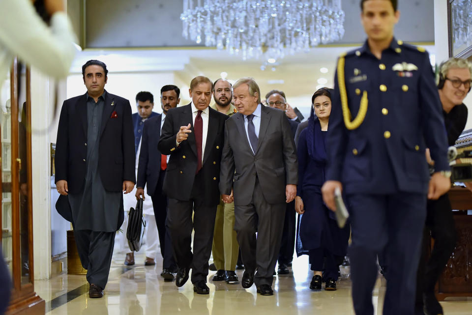In this handout photo released by Pakistan Prime Minister Office, U.N. Secretary-General Antonio Guterres, center, walk with Pakistan Prime Minister Shahbaz Sharif as they chat with each others at the Prime Ministry office in Islamabad, Pakistan, Friday, Sept. 9, 2022. Guterres appealed to the world to help Pakistan after arriving in the country Friday to see climate-induced devastation from months of deadly record floods that have left half a million people living in tents under the open sky.(Pakistan Prime Minister Office via AP)