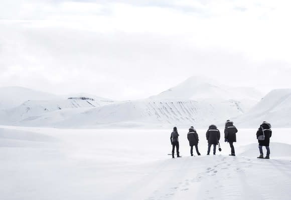 Five people wearing parkas standing on a snowy bank