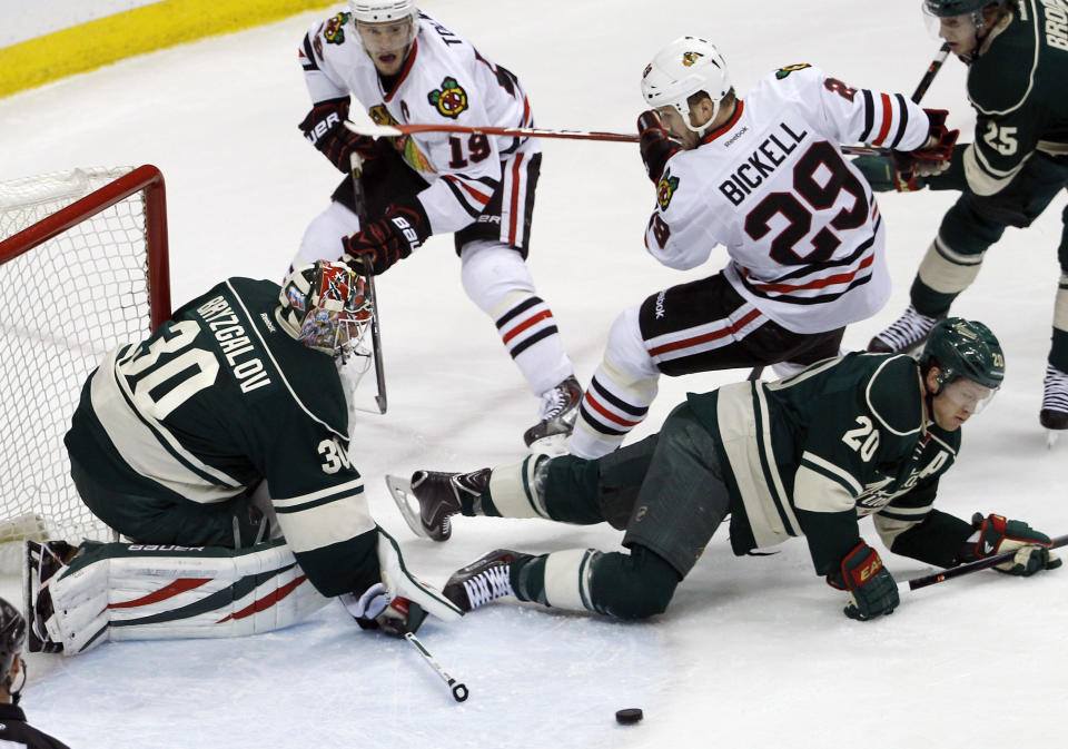 Chicago Blackhawks left wing Bryan Bickell (29) lands on Minnesota Wild defenseman Ryan Suter (20) as Wild goalie Ilya Bryzgalov (30), of Russia, deflects a shot during the first period of Game 6 of an NHL hockey second-round playoff series in St. Paul, Minn., Tuesday, May 13, 2014. (AP Photo/Ann Heisenfelt)