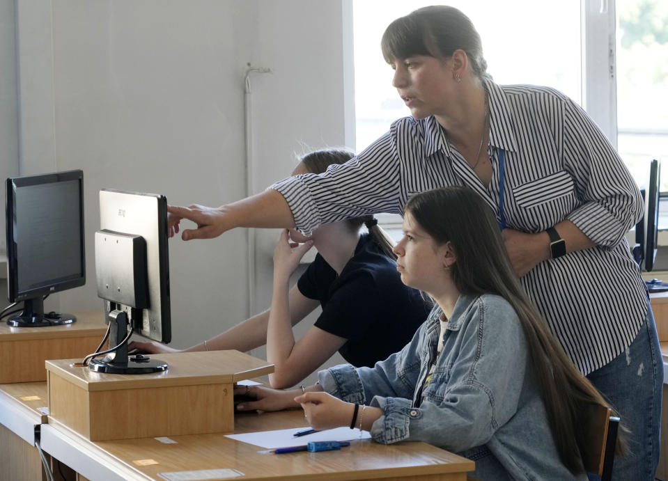 An exam administrator gives instructions to student Olha Andrieieva as she prepares to take the Ukrainian final state examination, a test after high school for those who hope to attend university, in Warsaw, Poland, Wednesday June 7, 2023. Russian forces have destroyed 262 educational institutions and damaged another 3,019 in their invasion of Ukraine, according to government figures. For those who've fled to other countries, schooling is suffering in unprecedented ways, according to families, educators, experts and advocates. The effects of war and relocation combined with the challenges of studying in a new country are compounding educational setbacks for young refugees. (AP Photo/Czarek Sokolowski)