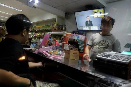 Men stand in a store as Thailand Prime Minister Prayuth Chan-ocha is seen on a TV during his weekly broadcast in Bangkok, Thailand, May 19, 2017. Picture taken May 19, 2017. REUTERS/Jorge Silva