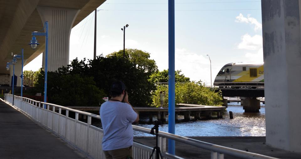 Matthew Casaliggi, 18, of Port St. Lucie, snaps photos of a Brightline train crossing the St. Lucie River September 22, 2023.