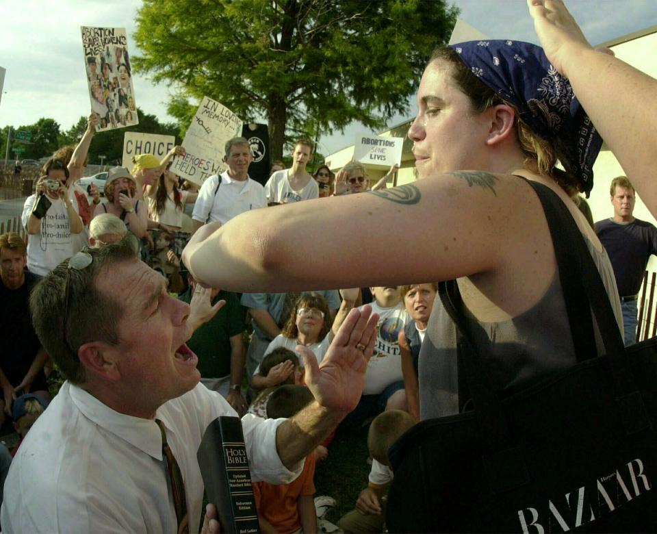 FILE - In this Saturday, July 14, 2001 file photo, abortion-rights activist Karen Nicholls of Chicago, right, shields herself from anti-abortion leader Rev. Flip Benham, left, as Benham attempts to pray for Nicholls during a protest by the two groups , at a Wichita, Kan., abortion clinic. (AP Photo/Charlie Riedel, file)