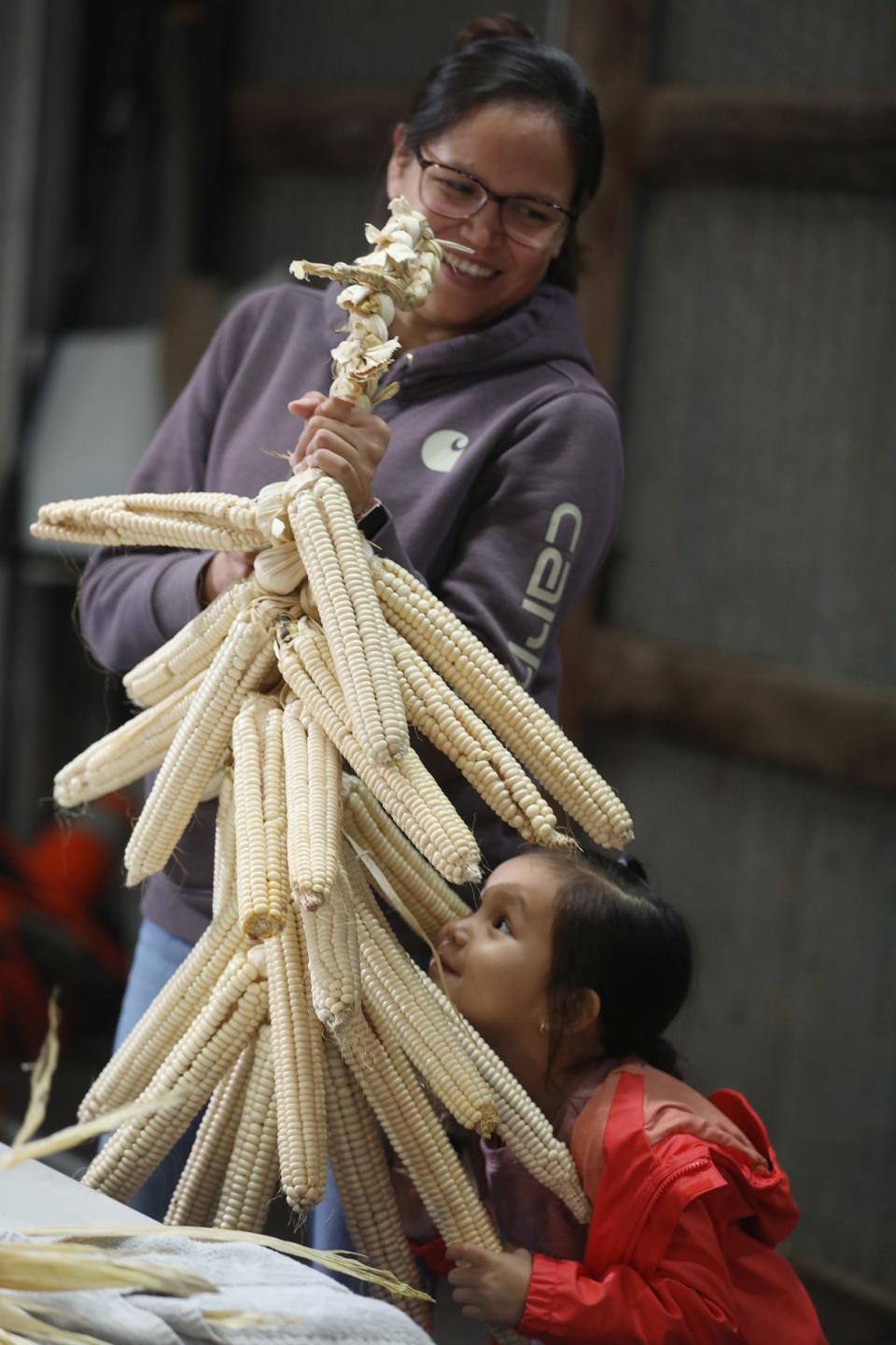 Nellie Cooke, Onondaga, who lives south of Syracuse on the Onondaga Nation, laughs as her daughter, Carolyn Hill, makes faces between the braided corn cobs.  Cooke had come with her mother, Andrea Cooke of Salamanca, on the Allegany Reservation, to help braid the corn for Ganondagan.