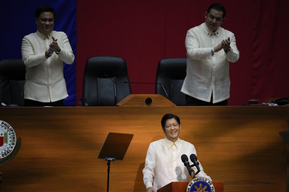 FILE - New Philippine President Ferdinand Marcos Jr., center, smiles as Senate President Juan Miguel Zubiri, left, and House Speaker Martin Romualdez applauds during his first state of the nation address in Quezon city, Philippines on July 25, 2022. Marcos Jr. has reaffirmed ties with the United States, the first major power he visited since taking office in June, in a key turnaround from the often-hostile demeanor his predecessor displayed toward Manila's treaty ally. (AP Photo/Aaron Favila, Pool, File)
