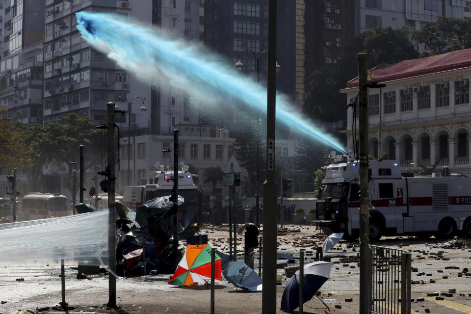 An armored police vehicle sprays blue-dyed liquid during a confrontation with protestors at the Hong Kong Polytechnic University in Hong Kong, Sunday, Nov. 17, 2019. (AP Photo/Ng Han Guan)