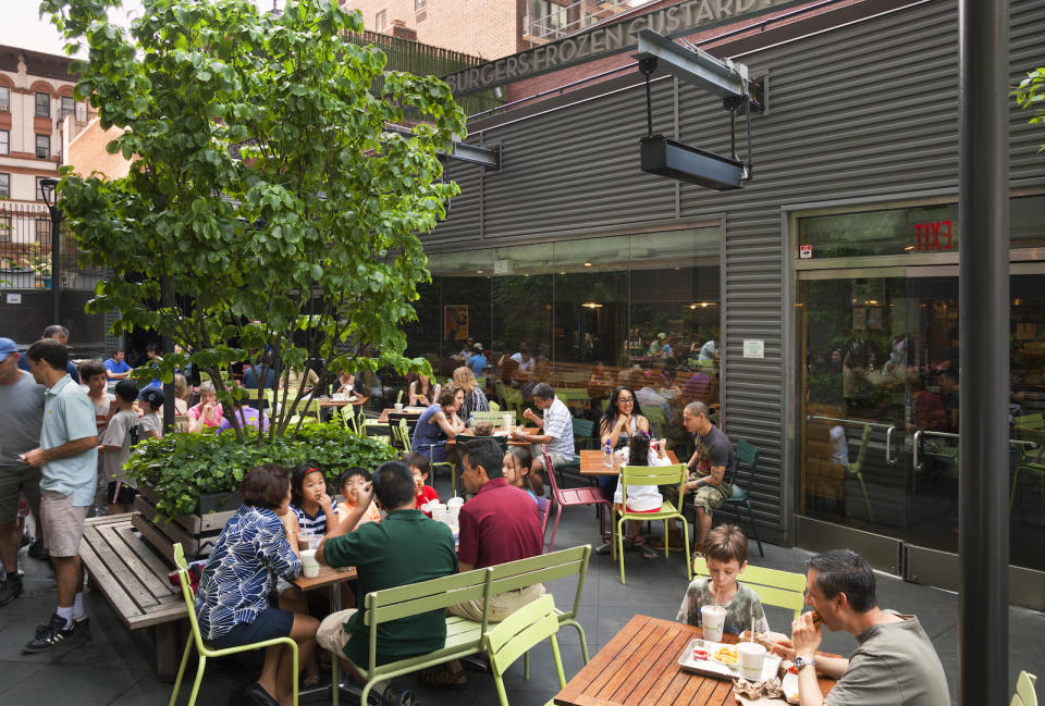 People eating at outside tables at a Shake Shack.