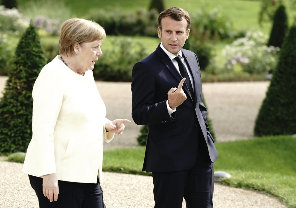 German Chancellor Angela Merkel, left and French President Emmanuel Macron talk in the garden of Meseberg Castle, the German government's guest house in Meseberg, Germany, Monday, June 29, 2020. Merkel met Monday with French President Emmanuel Macron for talks as Germany prepares to take over the European Union presidency. (Kay Nietfeld/dpa via AP)