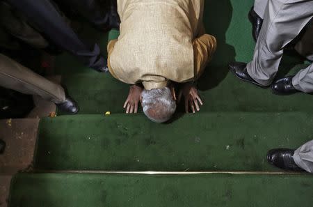 Narendra Modi bows down in respect at the steps of the parliament house upon his arrival to attend the BJP parliamentary party meeting in New Delhi May 20, 2014. REUTERS/Adnan Abidi