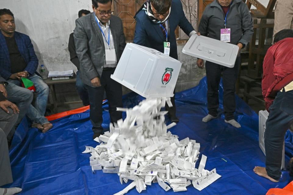 Election officials pour ballot papers from a ballot box for counting at a polling booth (AFP via Getty Images)