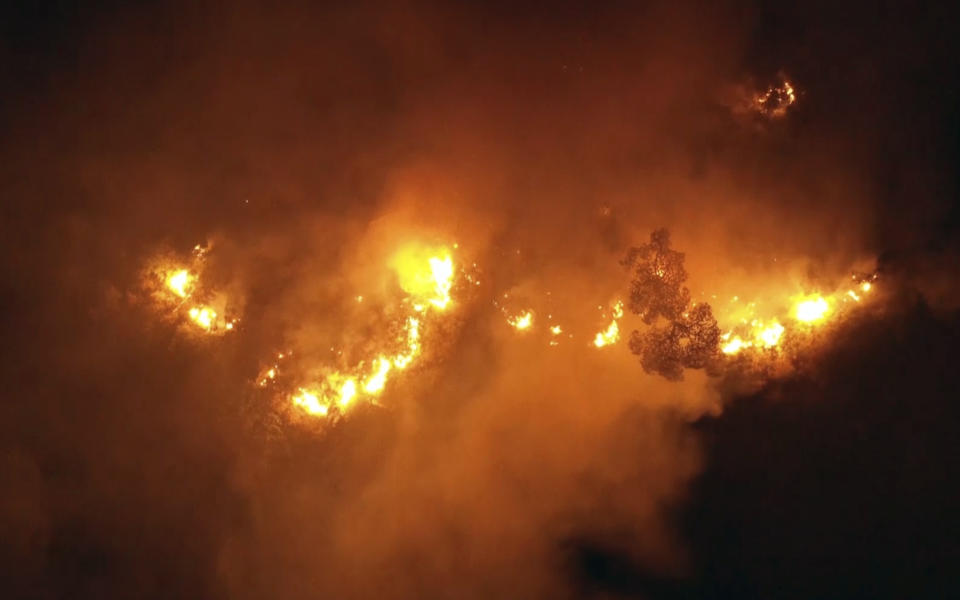 In this frame grab from video, flames rise at the scene of forest fire in Ras el-Harf village, in the Baabda district, Lebanon, Friday, Oct. 9, 2020. Wildfires around the Middle East triggered by a heatwave hitting the region have killed two people, forced thousands of people to leave their homes and detonated landmines along the Lebanon-Israel border, state media and officials said Saturday. (AP Photo)