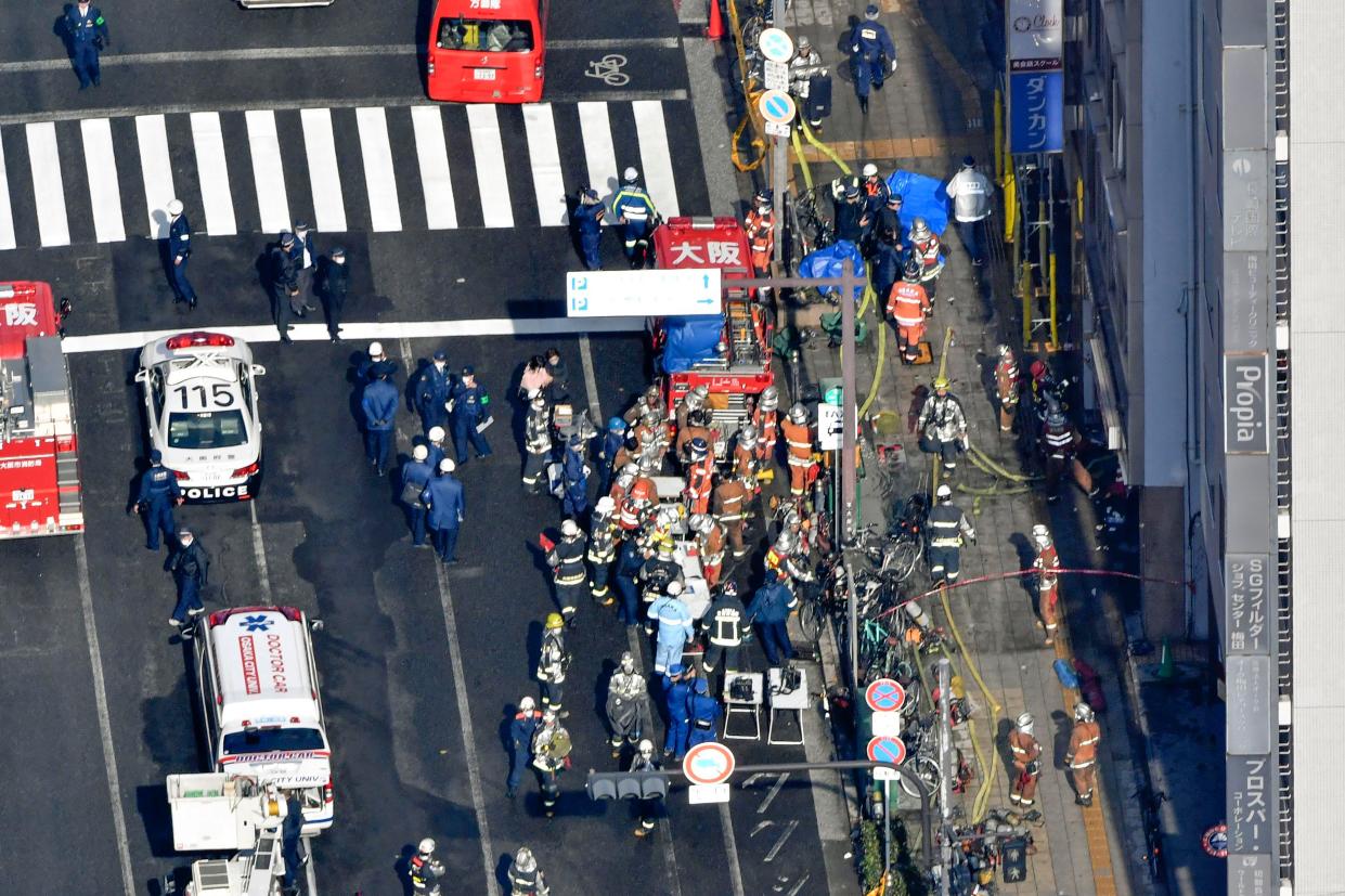 Policemen and firefighters gather near a building where a fire broke out in Osaka, western Japan Friday, Dec. 17. 