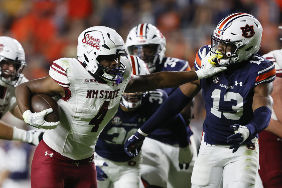 New Mexico State running back Star Thomas (4) stiff arms Auburn linebacker Cam Riley (13) as he carries the ball during the second half of an NCAA college football game Saturday, Nov. 18, 2023, in Auburn, Ala. (AP Photo/Butch Dill)