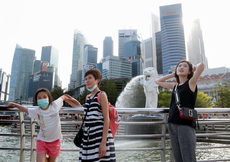 Tourists wearing protective face masks pose for photos at the Merlion Park in Singapore