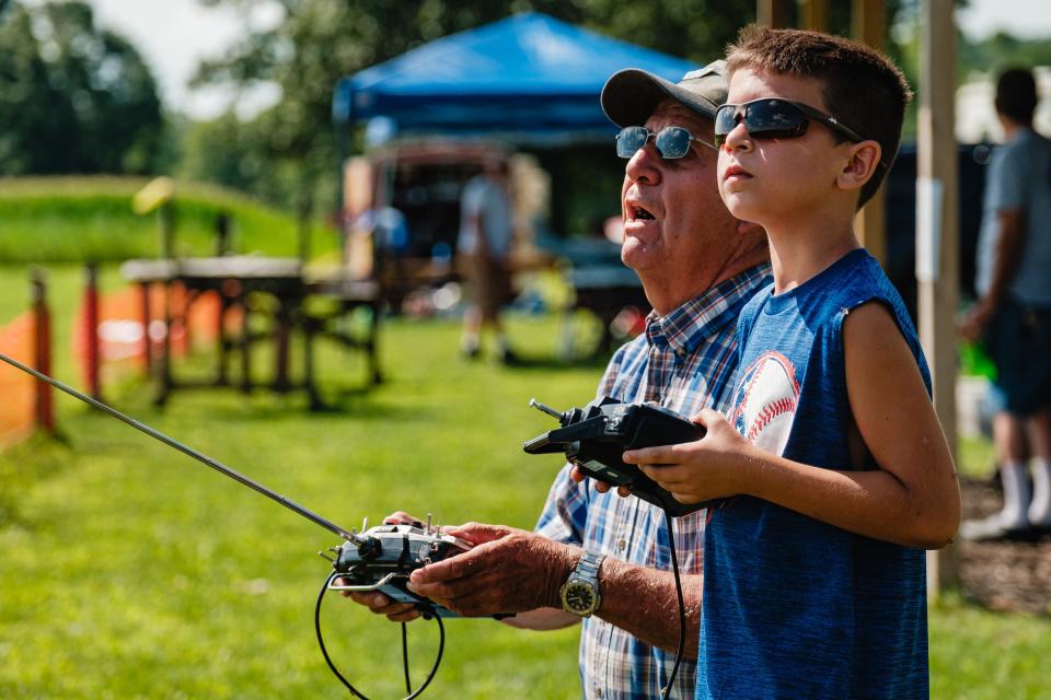 Marshall Zimmerman, right, of Navarre, learns to fly a remote controlled airplane with the assistance of pilot Jim Gowan, during the annual Academy of Model Aeronautics National Model Aviation Day hosted by the OldTown Valley Flyer's Club. A buddy box system was used for first-time flyers, in which the flight instructor could immediately take control through linked remote controls.