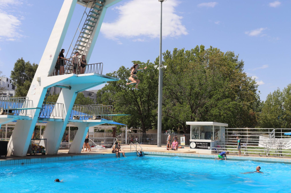 Pictured is a woman jumping from a diving platform at Canberra Olympic Pool. 