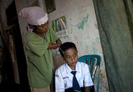 PURWOREJO, INDONESIA - MARCH 13: Armless professional photographer Rusidah, 44, combs her twelve-year-old son Nugraha's hair on March 13, 2012 in Purworejo, Indonesia. Rusidah shoots weddings and parties and has a small studio at home in the village of Botorejo, Bayan District, Purworejo, Central Java where her husband and son also reside. She has been in the photography business for nearly 20 years. (Photo by Ulet Ifansasti/Getty Images)