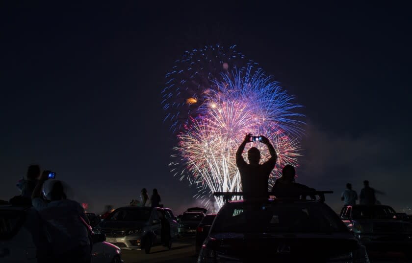 LOS ALAMITOS, CA - JULY 4, 2020: Southern California residents sit on the roofs of their vehicles to watch the fireworks during the Drive-Up 4th of July Spectacular at the Los Alamitos Joint Forces Training Base during the coronavirus pandemic on July 4, 2020 in Los Alamitos, California. (Gina Ferazzi / Los Angeles Times)