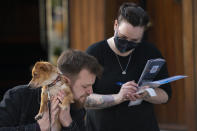 A customer and his dog orders outside a restaurant in Liverpool, England, Monday, April 12, 2021. Millions of people in England will get their first chance in months for haircuts, casual shopping and restaurant meals on Monday, as the government takes the next step on its lockdown-lifting road map. (AP Photo Jon Super)