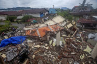 Motorists ride past buildings flattened by an earthquake in Mamuju, West Sulawesi, Indonesia, Saturday, Jan. 16, 2021. Damaged roads and bridges, power blackouts and lack of heavy equipment on Saturday hampered Indonesia's rescuers after a strong and shallow earthquake left a number of people dead and injured on Sulawesi island. (AP Photo/Yusuf Wahil)