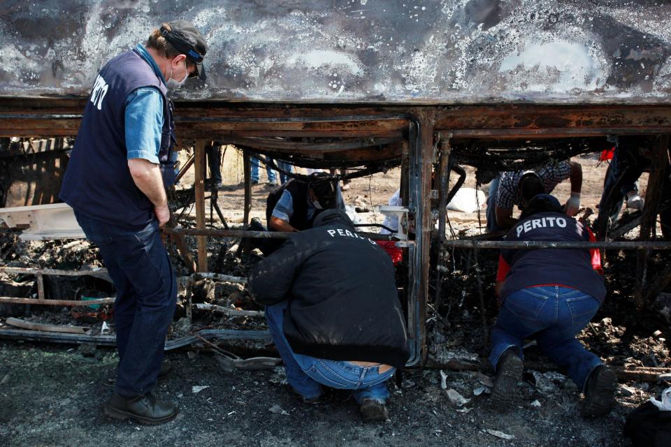 CORRECTS SPELLING OF PHOTOGRAPHER'S FIRST NAME - Forensic experts inspect a passenger bus that slammed into a broken-down truck and burst into flames near the town of Ciudad Isla in the Gulf state of Veracruz, Mexico, Sunday, April 13, 2014. Dozens of people traveling on the bus to Mexico City burned to death inside the bus. (AP Photo/Felix Marquez)