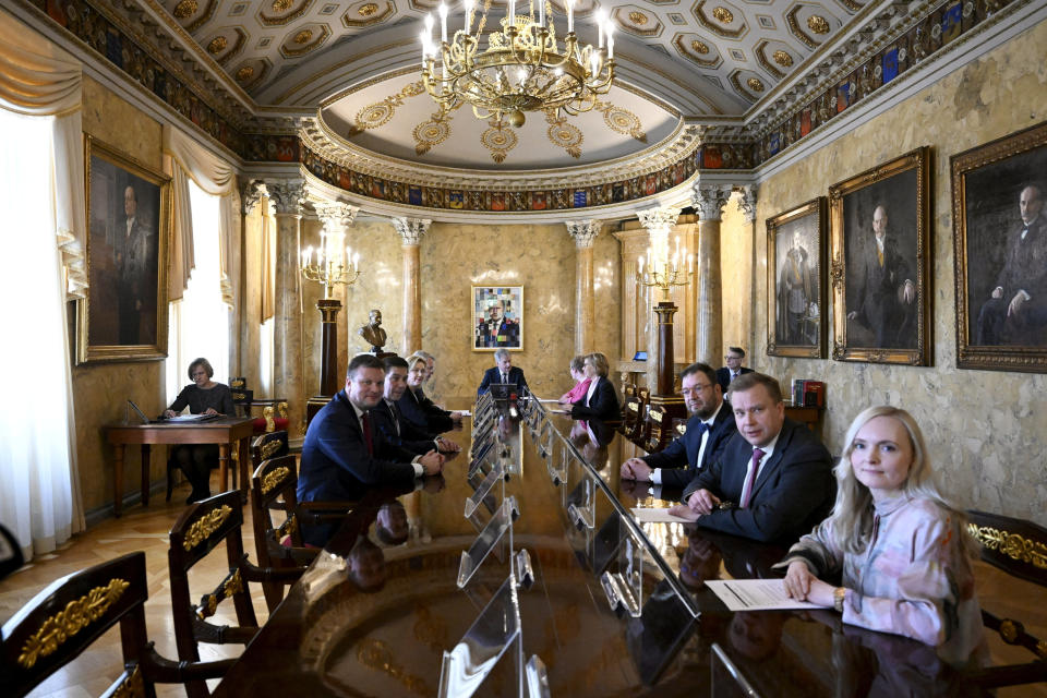 Finnish President Sauli Niinisto and others sit at a long table during a meeting.