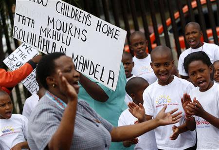 Orphans of Orlando Children's Home pay tribute to Nelson Mandela outside of his house on Vilakazi Street in Soweto, where the former South African president resided when he lived in the township, December 9, 2013. REUTERS/Yves Herman