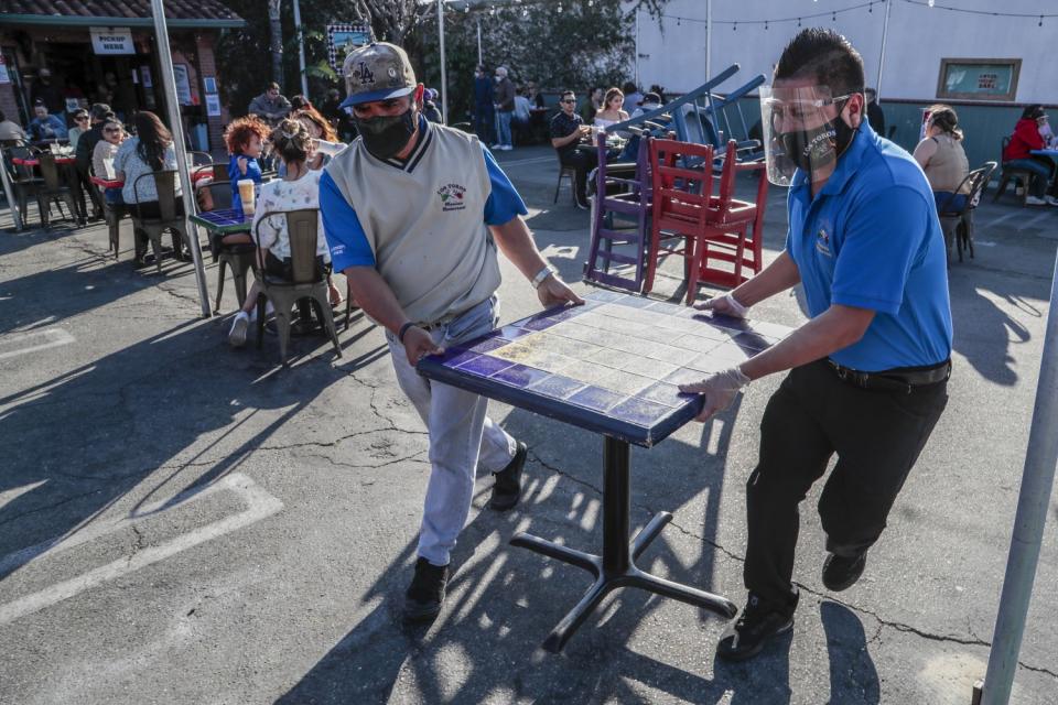 Nicolas Montano, left, and Jose Vasquez arrange restaurant tables