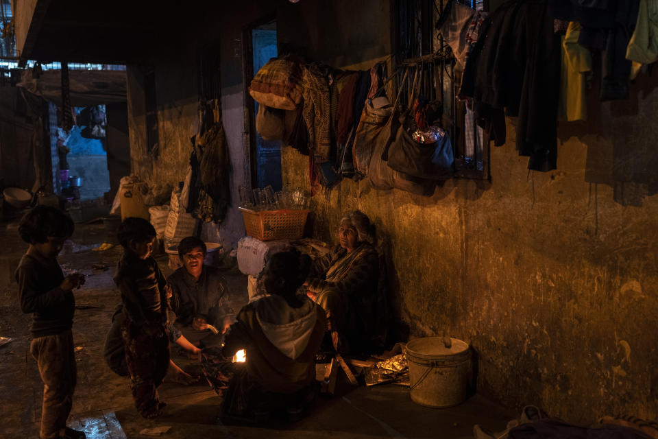 A homeless family gathers around a stove as they cook their evening meal in the compound of a dilapidated shelter for homeless people in New Delhi, Friday, Dec. 30, 2022. Even though the city’s night shelters are a refuge to many who would otherwise find themselves sleeping near traffic-busy roundabouts and underpasses, most people there live in harsh conditions. (AP Photo/Altaf Qadri)