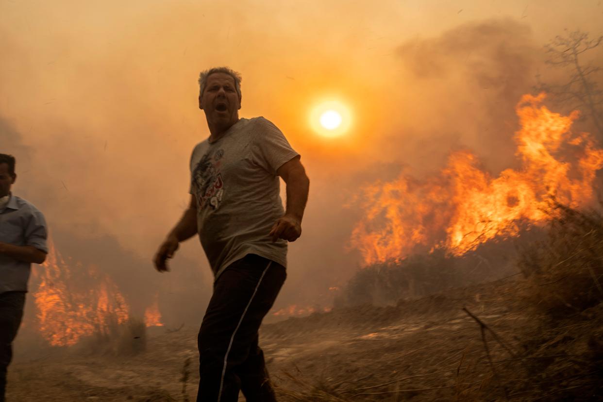 A local reacts as the flames burn trees in Gennadi village, on the Aegean Sea island of Rhodes (Copyright 2023 The Associated Press. All rights reserved)