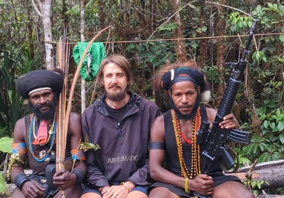 Philip Mark Mehrtens, 38, sits inbetween two West Papua Liberation Army soldiers after he was captured last year (Supplied)