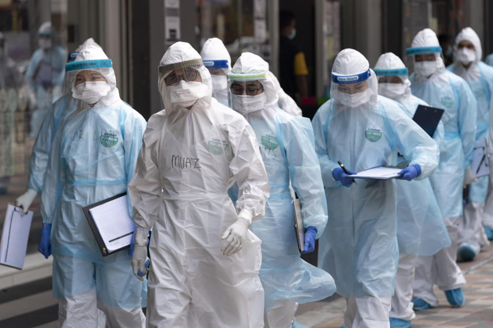 Medical workers in protective suits entering a building under lockdown in downtown Kuala Lumpur, Malaysia, on Tuesday, April 7, 2020. The Malaysian government issued a restricted movement order to the public to help curb the spread of the new coronavirus. The new coronavirus causes mild or moderate symptoms for most people, but for some, especially older adults and people with existing health problems, it can cause more severe illness or death. (AP Photo/Vincent Thian)