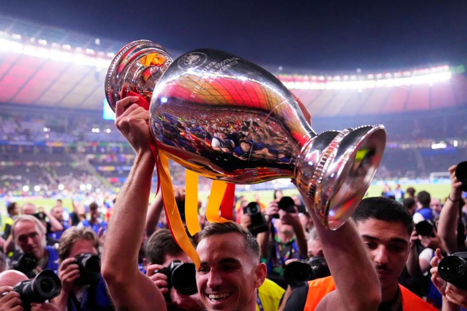 Spain's Dani Olmo holds up the trophy to the fans after winning the final match between Spain and England (AP)