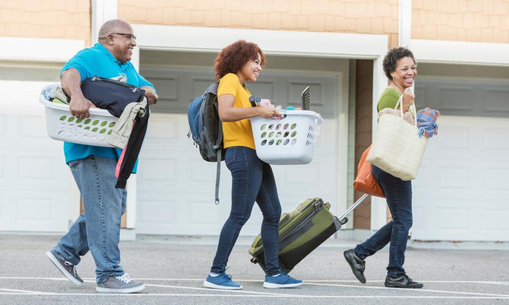 African-American parents helping daughter moveMature African-American parents helping their daughter relocate, perhaps into an apartment or college dorm. They are walking and talking, carrying the young woman's household belongings in laundry baskets and a suitcase.