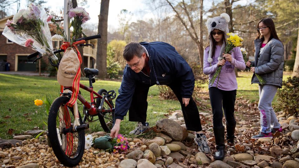 Jason Hoffman places flowers at a makeshift memorial outside the home of Elrey "Bud" and June Runion in January 2015 in Marietta, Goergia. - David Goldman/AP
