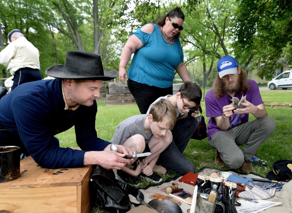 Dressed as a Civil War soldier Illinois State Museum volunteer Paul Golladay, left, talks to folks about some of the things a union soldier would carry as they look over replicas of those kind of items at the museum Saturday, May, 6, 2023. The museum had living history exhibits out front as part of the commemoration of the Illinois National Guard's 300 anniversary. 