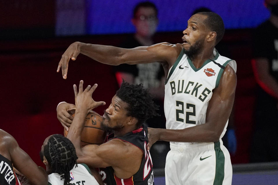Miami Heat's Jimmy Butler, center, is defended by Milwaukee Bucks' Khris Middleton (22) in the second half of an NBA conference semifinal playoff basketball game Friday, Sept. 4, 2020, in Lake Buena Vista, Fla. (AP Photo/Mark J. Terrill)