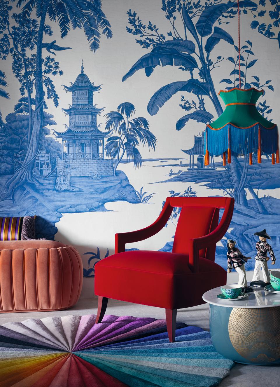 A living room with a bold red chair and blue wallpaper