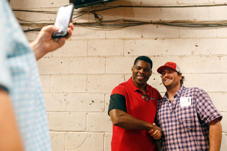 Republican Senate candidate Herschel Walker poses for a photo with a supporter at the Northeast Georgia Livestock Barn in Athens, Ga., on Wednesday, July 20, 2022. Walker spoke about gas prices and the November election. 