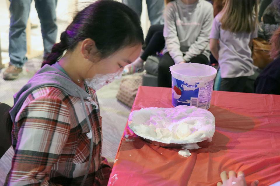 A participant goes digging for gummy worms in a pie of whipped cream during Pi Day at a previous Spring Break Camp at the Don Harrington Discovery Center.