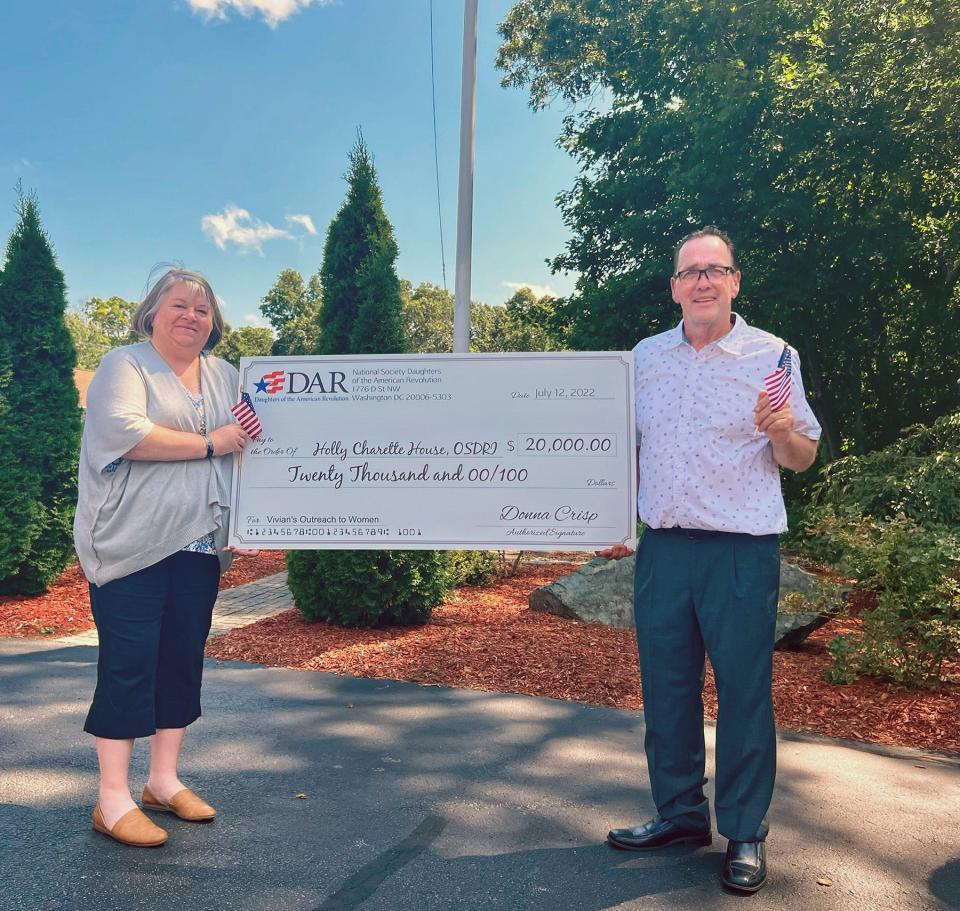 Regina and Edward Roberts hold a representation of the $20,000 check donated to the house for female veterans named after their late daughter, Holly Charette, a Marine who was killed in Iraq in 2005.